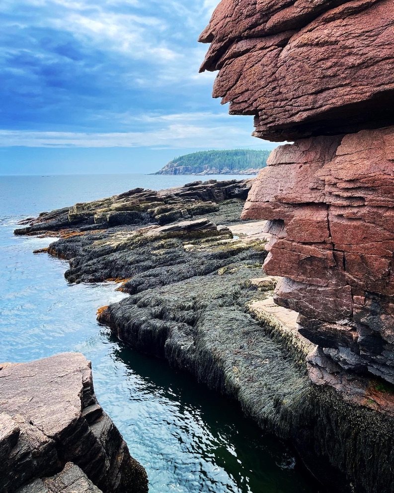 Red layered sedimentary rock formations with tidal pools